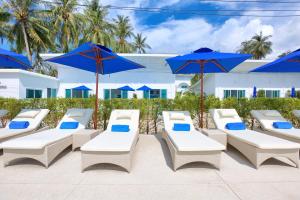 a row of white chairs and blue umbrellas at La Perle Resort Koh Samui in Mae Nam