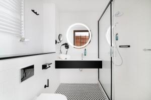 La salle de bains blanche est pourvue d'un lavabo et d'un miroir. dans l'établissement Focus Hotel Premium Lublin, à Lublin