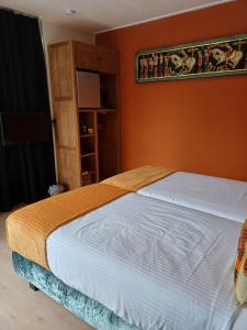 uma cama num quarto com uma parede laranja em East Meets West Bed and Breakfast em Veenendaal