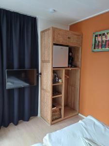 um quarto com um armário com uma televisão em East Meets West Bed and Breakfast em Veenendaal