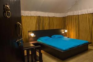 a bedroom with a bed with blue sheets and a table at Trident Jungle Stay in Dandeli