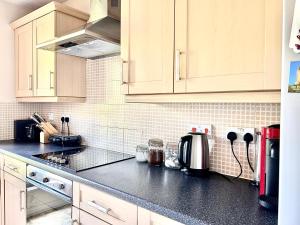 uma cozinha com armários brancos e um balcão preto em Spekman's 3 Bedroom Ap - 20min Glasgow & Edinburgh em Falkirk