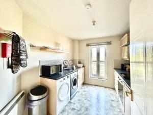 uma pequena cozinha com máquina de lavar e secar roupa em Spekman's 3 Bedroom Ap - 20min Glasgow & Edinburgh em Falkirk