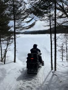 eine Person, die mit einem Schneemobil durch den Schnee fährt in der Unterkunft Auberge Boréale de Charlevoix in Petit-Saguenay