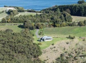 eine Luftansicht eines Hauses auf einem Hügel mit dem Meer in der Unterkunft Great Ocean Road Wellness and Nature Stay in Apollo Bay