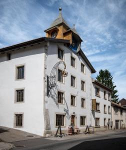 a large white building with a clock tower at Hôtel-Restaurant Le Cochon Rose in La Sagne