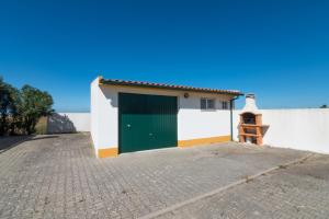 a white and green building with a green garage at Tilli'n'Joe's Beach House in Atouguia da Baleia