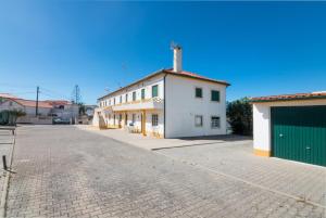 an empty street with a white building with a green garage at Tilli'n'Joe's Beach House in Atouguia da Baleia