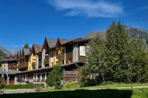 un grand bâtiment avec un panneau devant lui dans l'établissement Blu Hotel Acquaseria, à Ponte di Legno