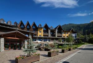 un complexe avec des arbres et des parasols dans une cour dans l'établissement Blu Hotel Acquaseria, à Ponte di Legno