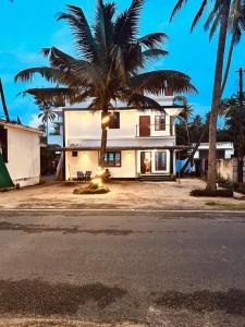 a house with a palm tree in front of it at ENOCEAN HOMESTAY in Cherai Beach