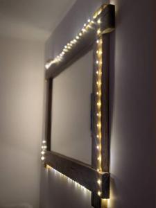 a wooden mirror with lights on a wall at Modern cosy apartment walking distance to many cove beaches and coast path walks as well as the famous Helford river in Falmouth