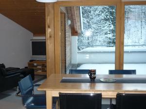 comedor con mesa, sillas y ventana en Moderne attraktive Dachwohnung für max. 6 Personen in ruhiger Umgebung, en Flims