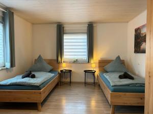 two beds in a room with two windows at Gästehaus Trockau in Pegnitz