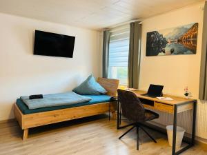 a room with a bed and a desk with a laptop at Gästehaus Trockau in Pegnitz