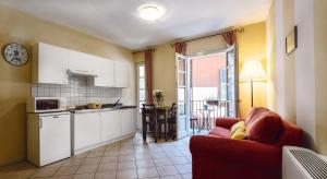 a living room with a red couch and a kitchen at Residenza dei Fiori in Cannero Riviera