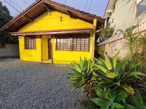 une maison jaune avec une porte jaune et quelques plantes dans l'établissement RCM Vilas - YELLOW HOUSE, à Joinville