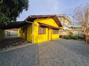 une maison jaune avec une allée devant elle dans l'établissement RCM Vilas - YELLOW HOUSE, à Joinville