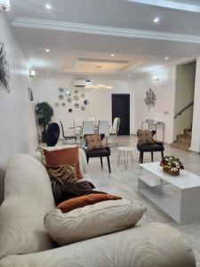 ein Wohnzimmer mit einem weißen Sofa und Stühlen in der Unterkunft Dvyne Lux Home - Off Ikeja in Ikeja