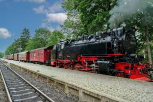 um comboio preto e vermelho está nos carris em Pension zum Hexenstieg em Schierke