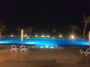 una piscina por la noche con dos sillas y una sombrilla en Sunrise Sifah, en As Sīfah