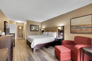 a hotel room with a bed and a red chair at Holiday Inn Hotel Peterborough Waterfront, an IHG Hotel in Peterborough