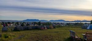 a field with a view of a city and mountains at Camping Güino in Puerto Natales