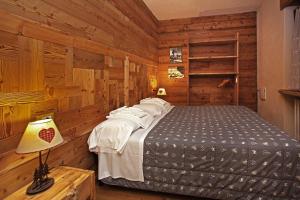 a bedroom with a bed in a room with wooden walls at Eydappartamenti in Sauze dʼOulx