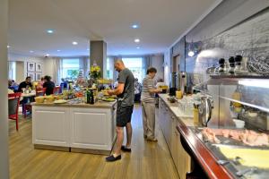 duas pessoas a preparar comida numa cozinha de restaurante em Hotel La Siesta & Medical Spa em Jastrzębia Góra