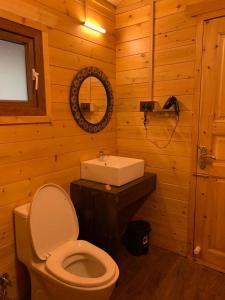 La salle de bains en bois est pourvue de toilettes et d'un lavabo. dans l'établissement Maruti Villa, à Kodaikānāl