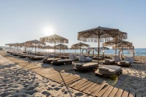 una fila de sombrillas y tumbonas en una playa en Pnoe Breathing Life - Adults Only, en Karteros