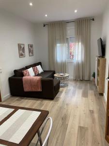 un soggiorno con divano nero e pavimento in legno di Nice Apartment 2 Bedrooms Well Connected a Cornellà de Llobregat