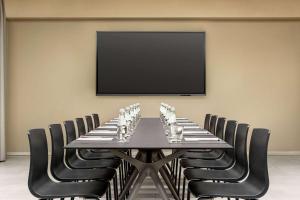 a conference room with a table with chairs and a flat screen tv at Amedia Milan, Trademark Collection by Wyndham in Milan