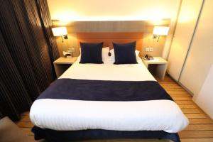 a large bed in a hotel room with two tables at Logis Hôtel Les Tuileries in Féy