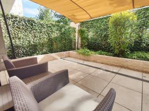 a patio with two chairs and an umbrella at Spa Residence Carbona Mona Lila Apartman in Hévíz