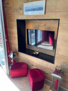 sala de estar con 2 taburetes rojos y TV de pantalla plana en Luxury apartment, en Crans-Montana