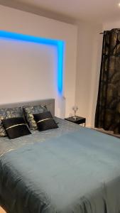 una camera da letto con un grande letto con una luce blu di Maison jardin paisible 1 chambre a Mérignac