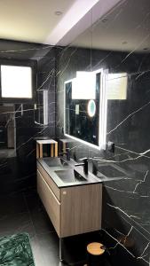 bagno nero con lavandino e specchio di Maison jardin paisible 1 chambre a Mérignac