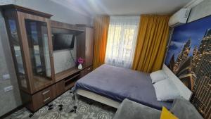 een slaapkamer met een bed, een dressoir en een tv bij 1-ком в центре Шымкента Аскарова 3 in Simkent