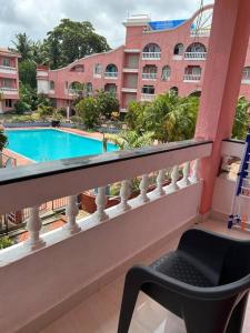 d'un balcon avec une chaise et une piscine. dans l'établissement Spacious Studio & Pool facility., à Benaulim