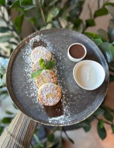 a plate of donuts with powdered sugar and a sauce at Apartments Domovik Myru St. 11s/21 in Mukacheve