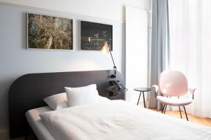 a bedroom with a white bed and a pink chair at Hotel Schützen Rheinfelden in Rheinfelden