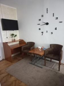 um quarto com uma mesa e um relógio na parede em Dvorska oaza em Sremski Karlovci