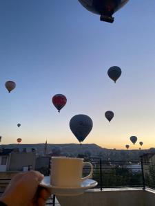 ギョレメにあるRustic Cavesの熱気球を持つコーヒーを持つ者