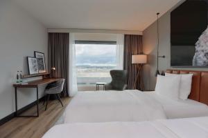 een hotelkamer met een bed, een bureau en een raam bij Radisson Blu Hotel Zurich Airport in Kloten