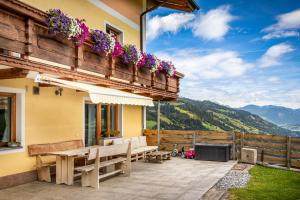 um pátio com bancos e flores num edifício em Brennergut Ferienwohnung am Bauernhof em Mühlbach am Hochkönig