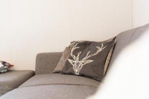 a gray couch with a black and white pillow on it at Heerlijk Huisje Hoenderloo in Hoenderloo