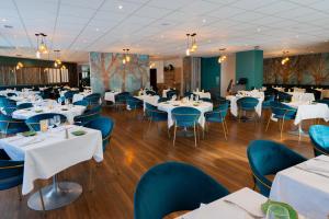 une salle à manger avec des tables blanches et des chaises bleues dans l'établissement Hôtel & Restaurant des Remparts, à Rochefort