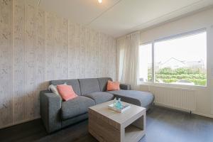 - un salon avec un canapé et une table dans l'établissement Beach Appartement 14 - Callantsoog, à Callantsoog