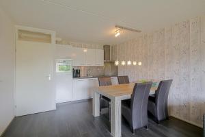 Il comprend une cuisine et une salle à manger avec une table et des chaises en bois. dans l'établissement Beach Appartement 14 - Callantsoog, à Callantsoog